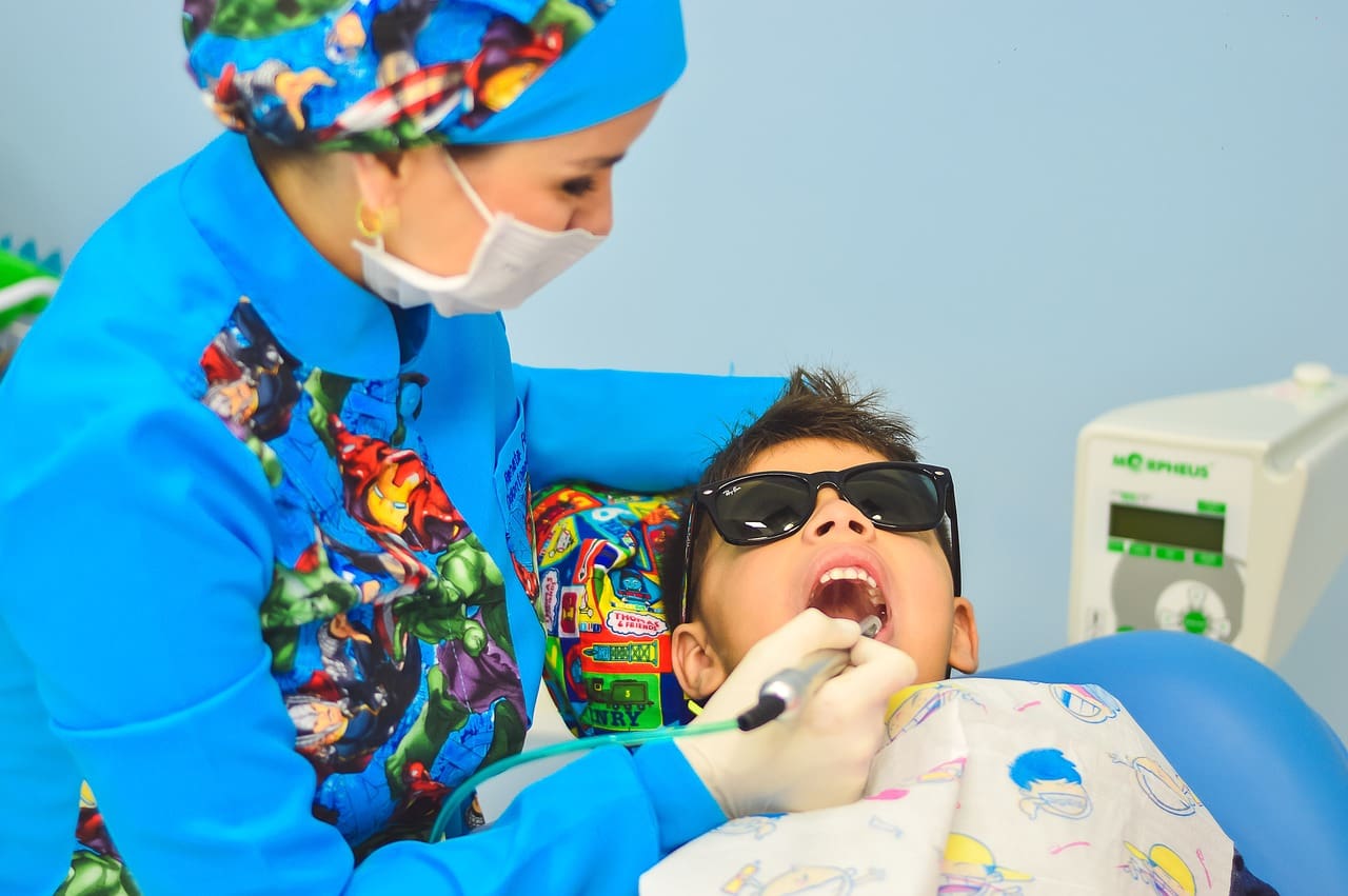 A child is getting his teeth checked by an adult.