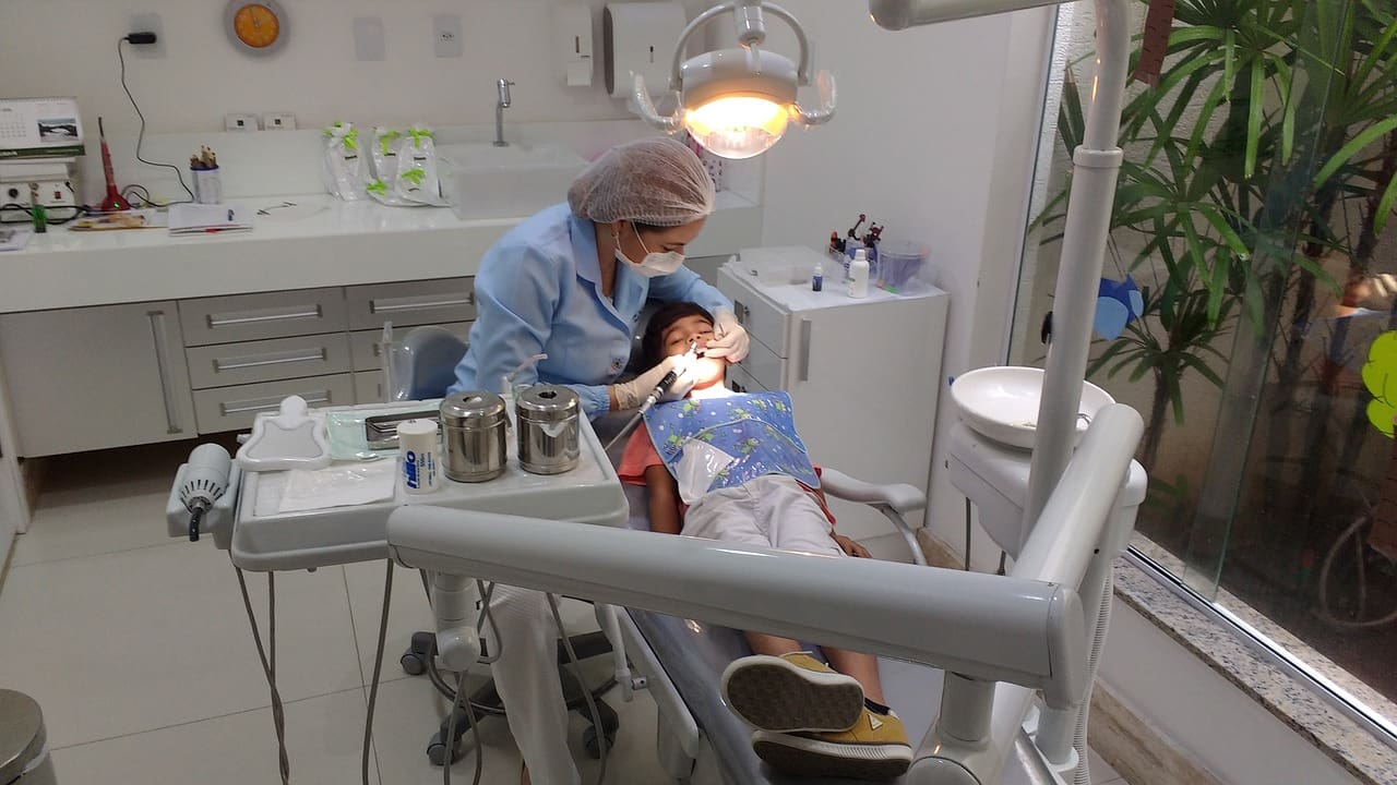 A dentist is examining the teeth of a young patient.