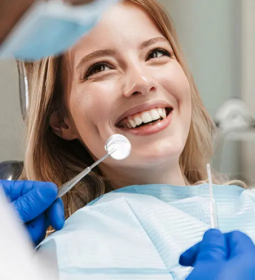 A woman is smiling while being examined by an dentist.