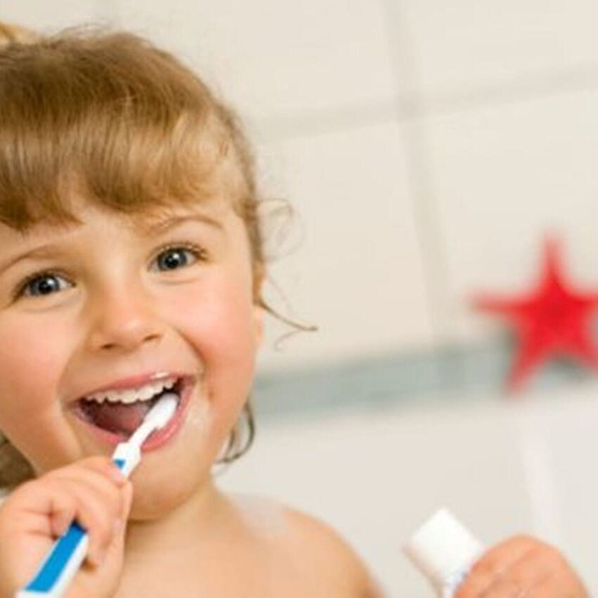 A little girl is brushing her teeth with an electric toothbrush.