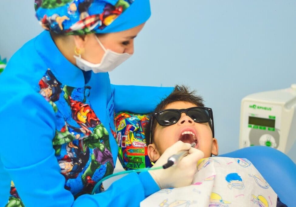A child is getting his teeth checked by an adult.