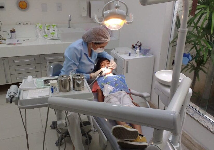 A dentist is examining the teeth of a young patient.